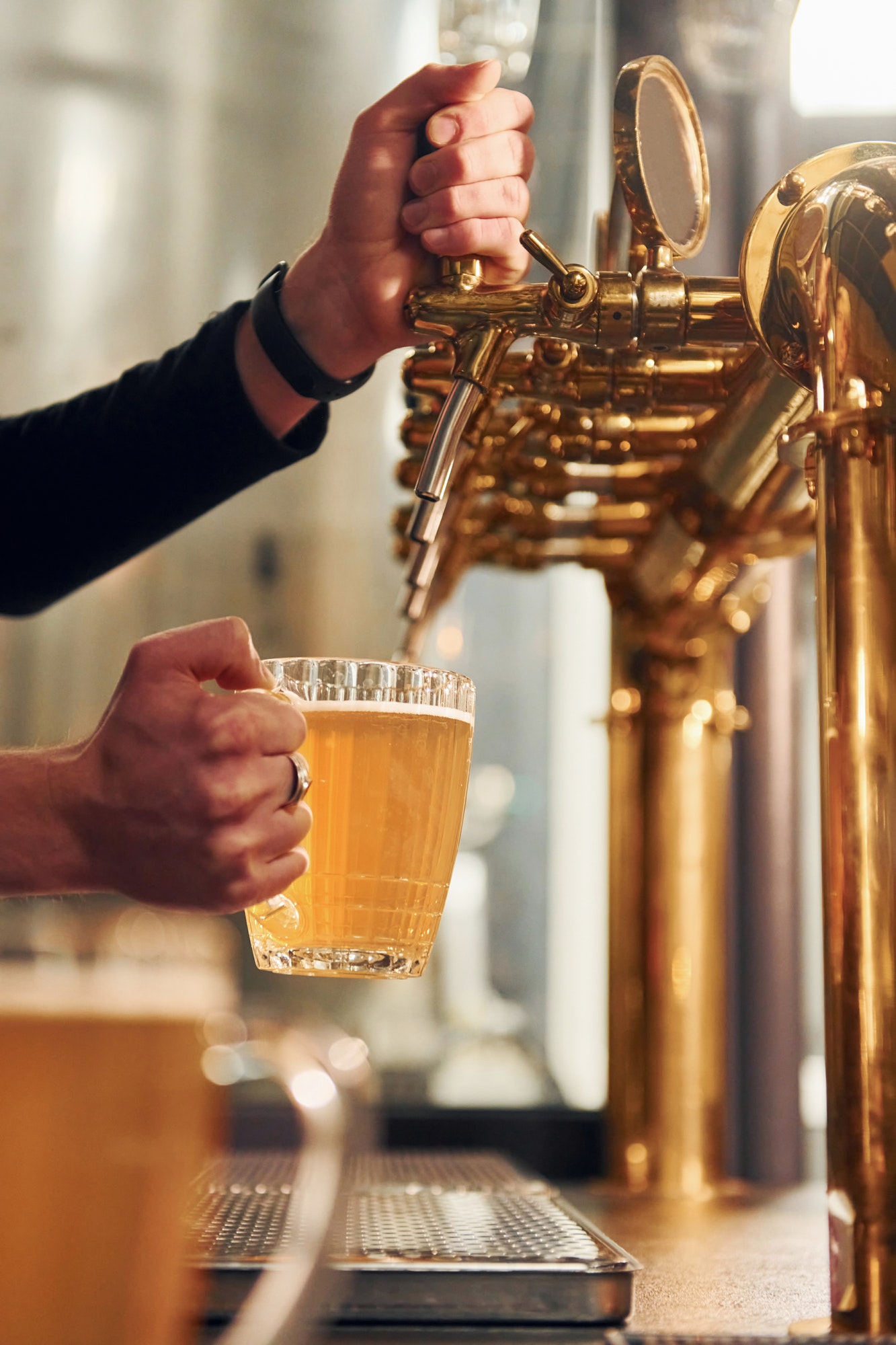 Side view of man's hands that fills glasses by beer